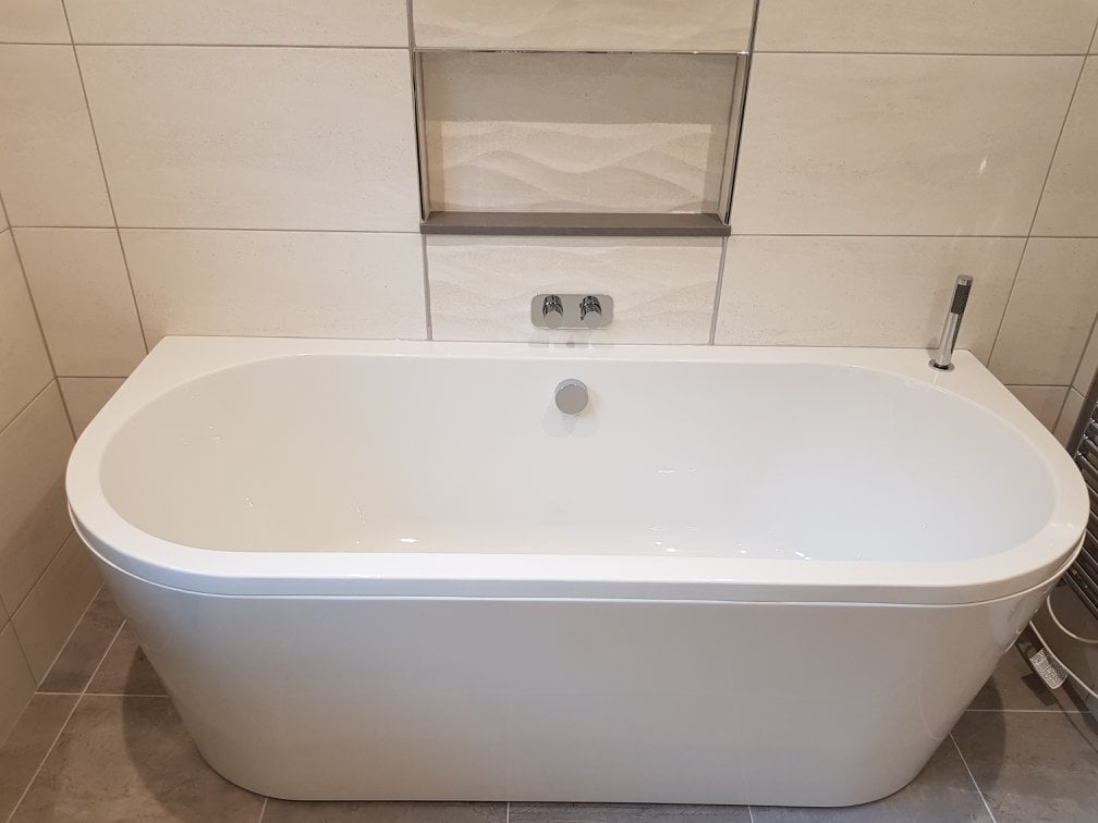 Curved White Bathtub Surrounded By Large White Tiles